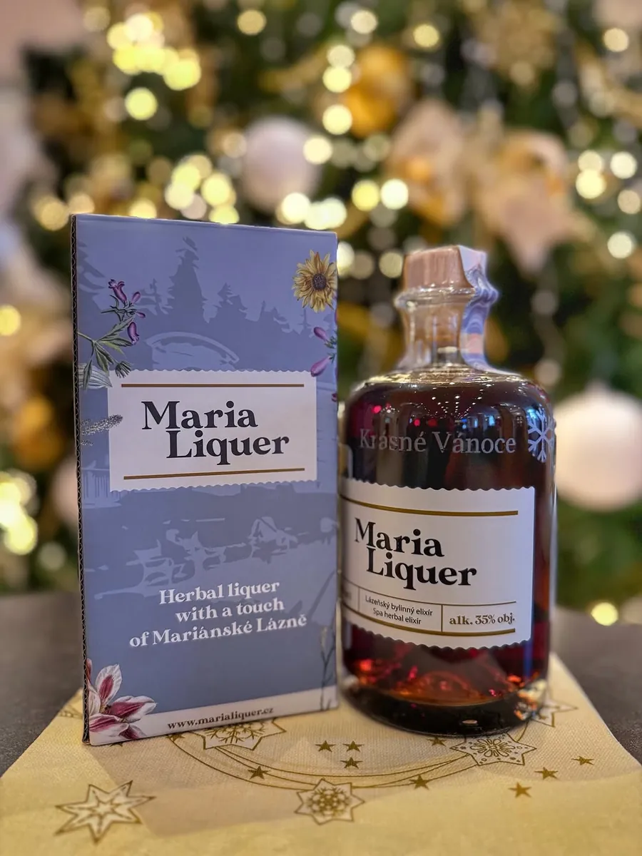 Lahev Maria Liquer s gravírováním Krásné Vánoce vedle dárkové krabičky pod vánočním stromkem